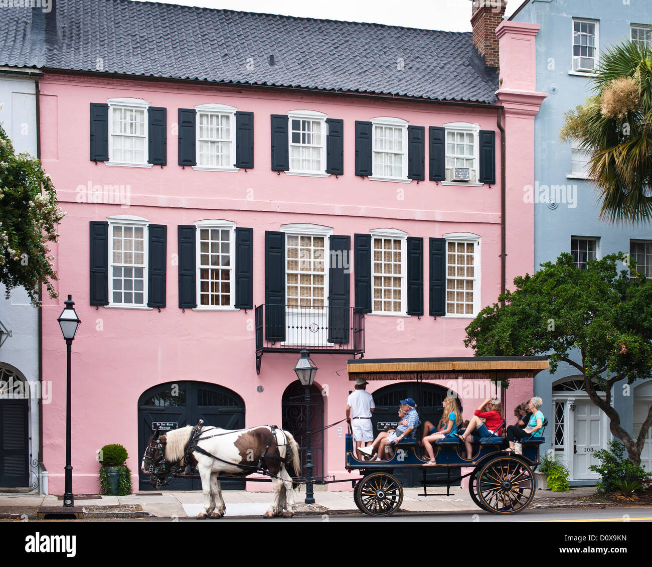 A guide in a horse carriage takes tourists through the historic colonial streets of Charleston Stock Photo