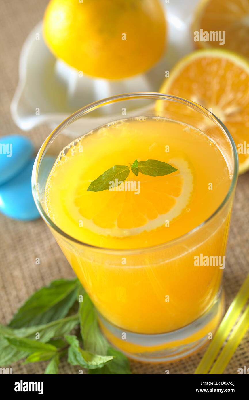 Freshly squeezed orange juice with orange slice and mint on top of the