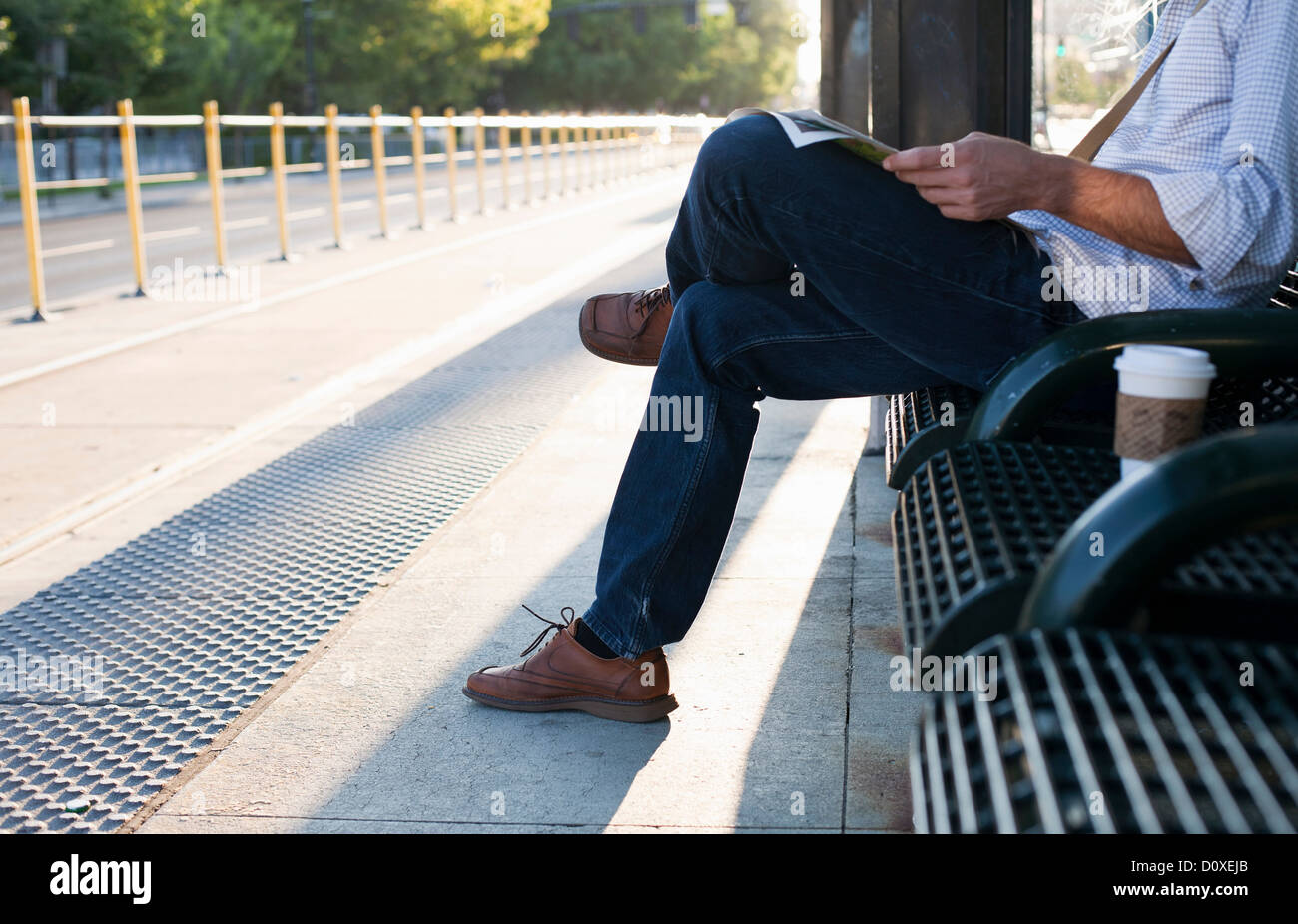 Man waiting on bench at railway station Stock Photo
