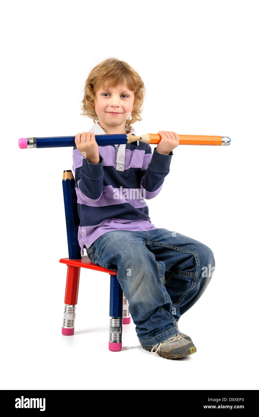 Young happy student seated in a chair with big pencils isolated in ...