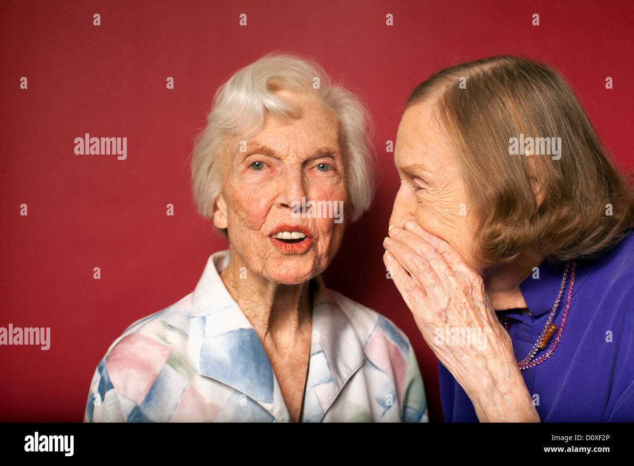 Portrait of two senior women whispering Stock Photo