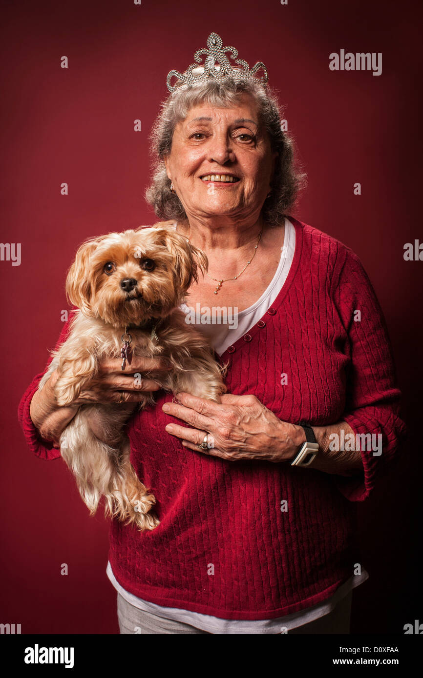 Senior woman holding dog and wearing a tiara Stock Photo