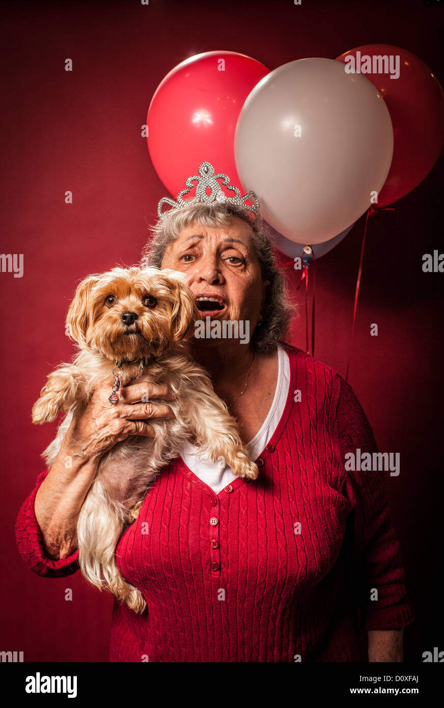 Senior woman holding dog and wearing a tiara Stock Photo