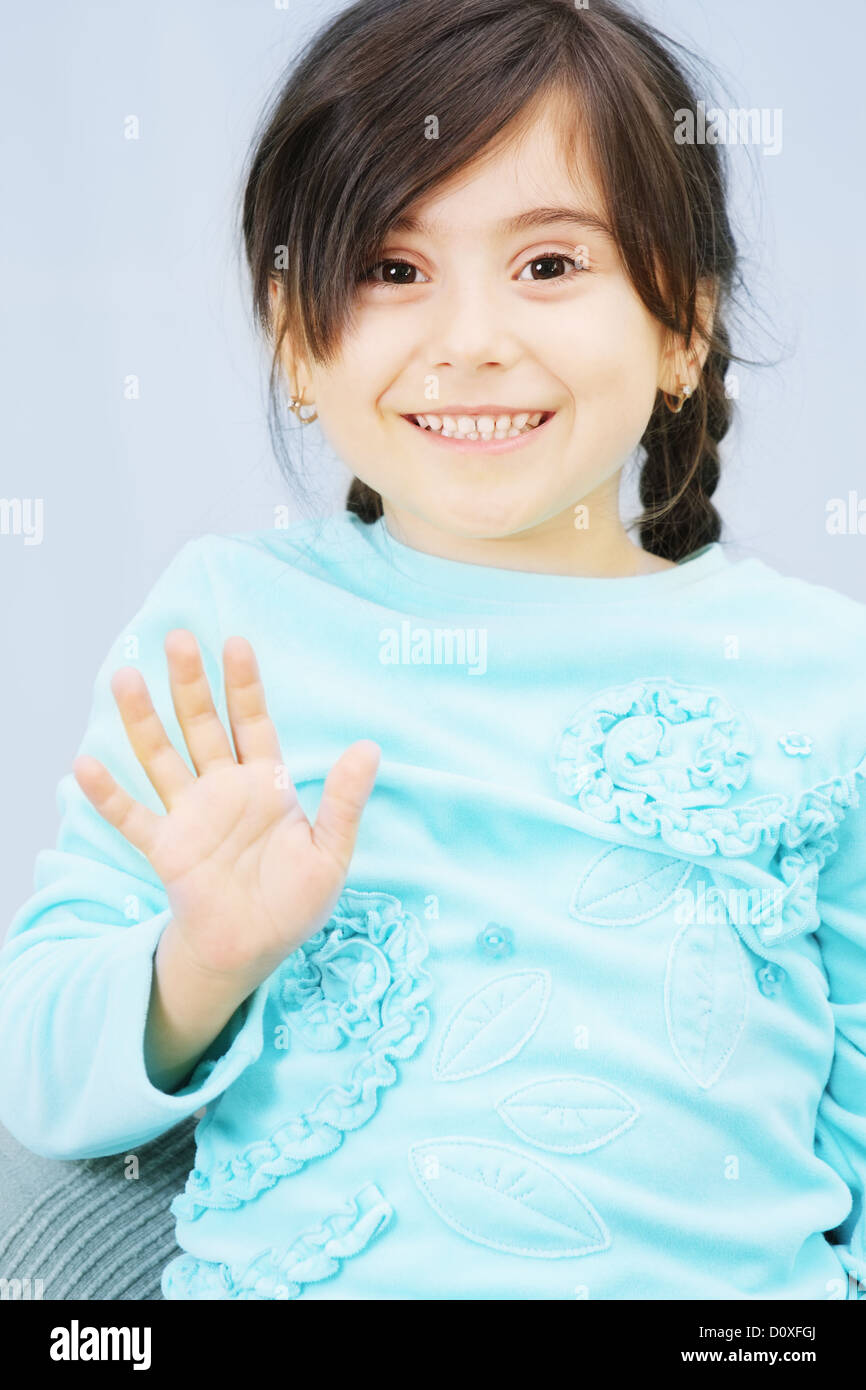 Little girl raises hand in waving Stock Photo