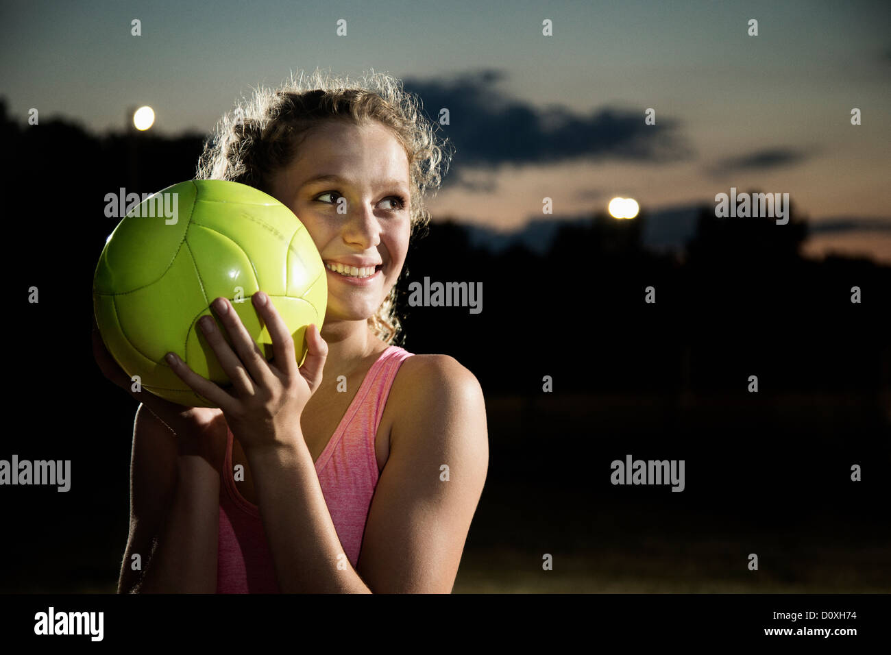 Girl holding soccer ball at night Stock Photo