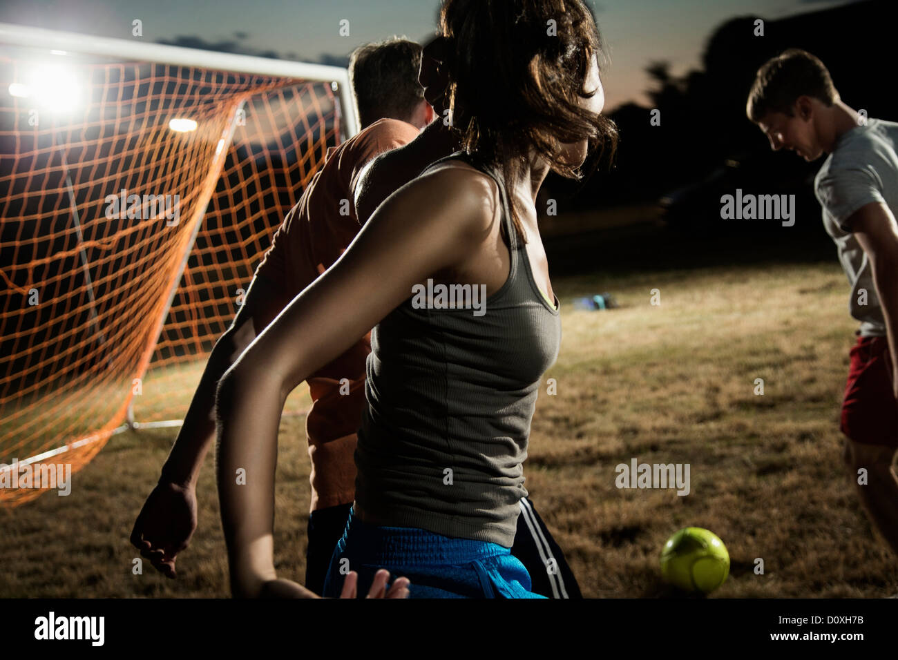 Friends playing soccer at night Stock Photo