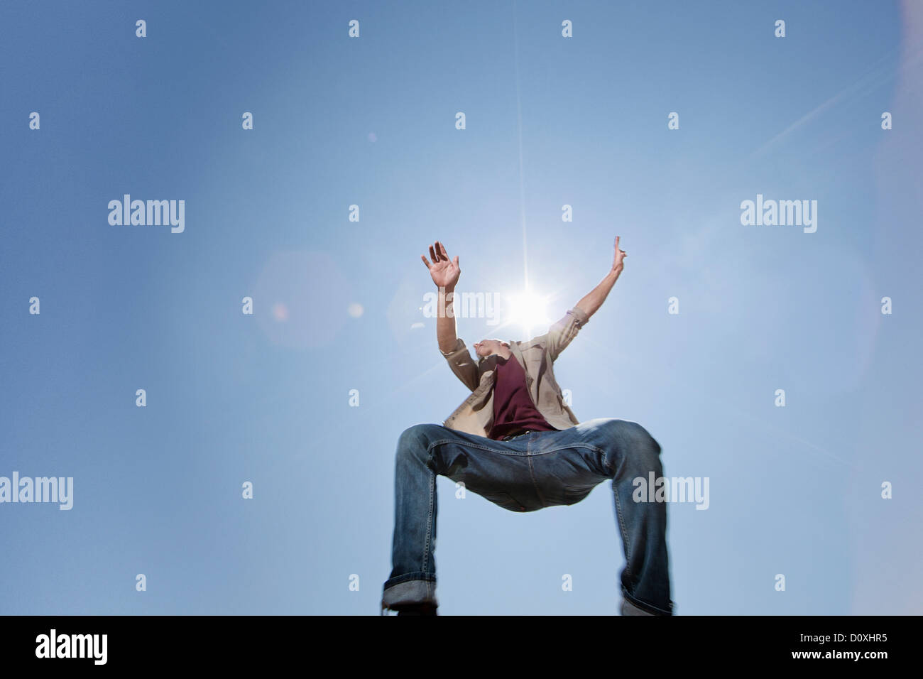 Young man jumping against blue sky, low angle Stock Photo