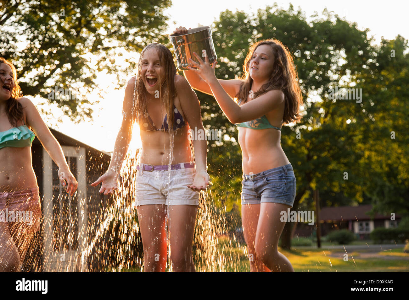 Girl pouring bucket of water over friend's head Stock Photo