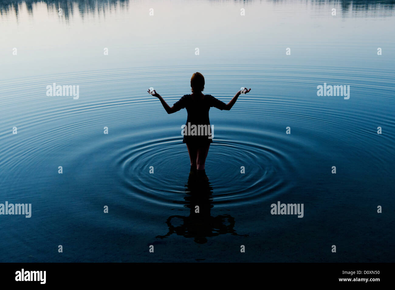 Woman meditating in peaceful lake Stock Photo