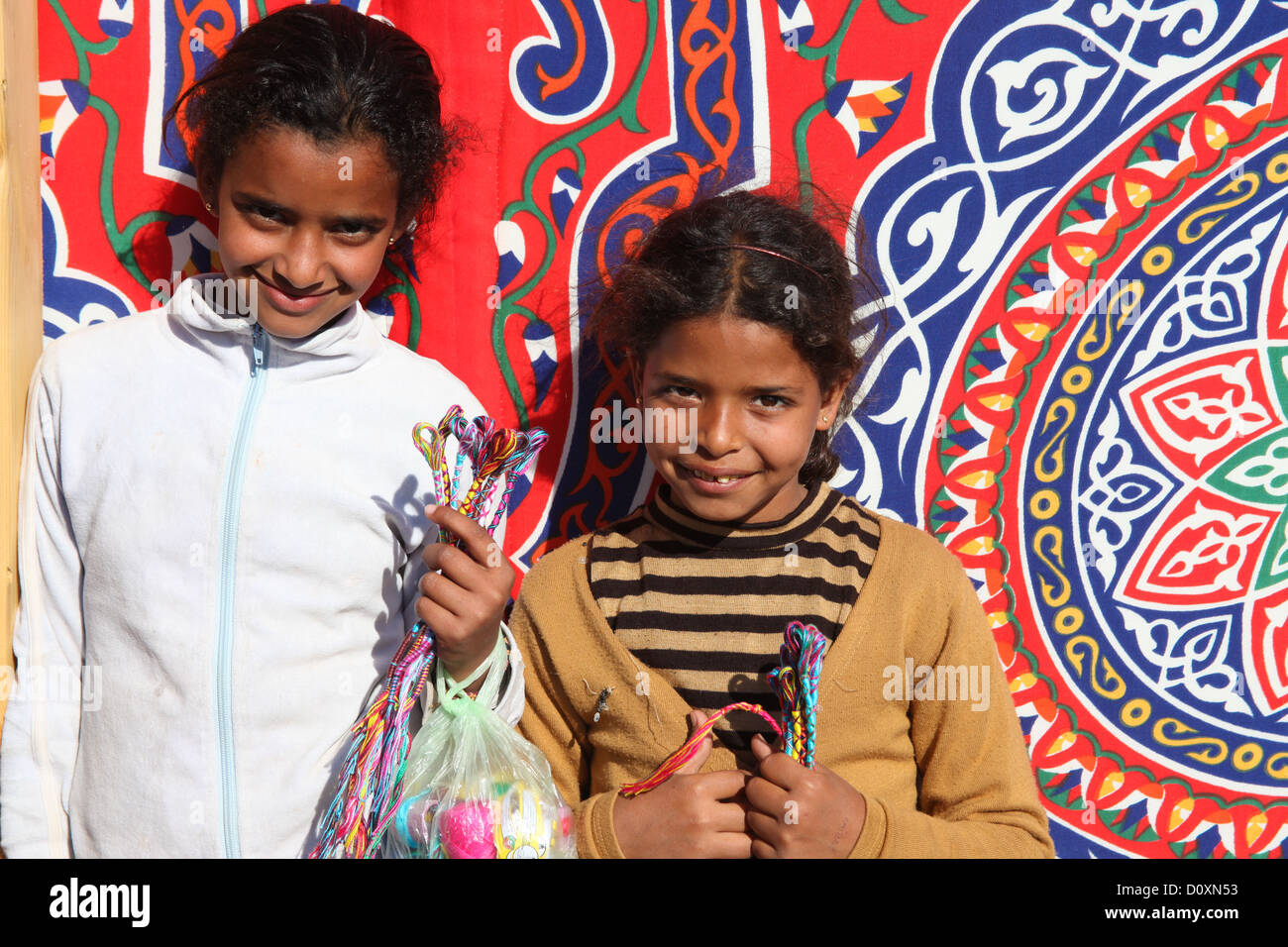 DAHAB - JANUARY 23. Young street sellers showing off their bracelets in Dahab, Egypt. It provides income for their families. Stock Photo