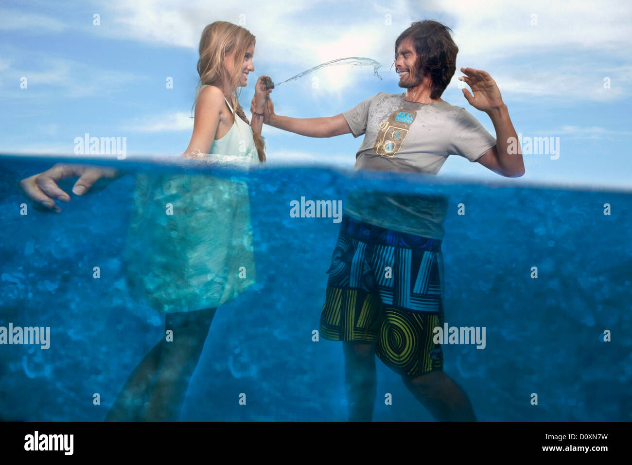 A couple plays with a fake camera dressed inside a swimming pool. Stock Photo