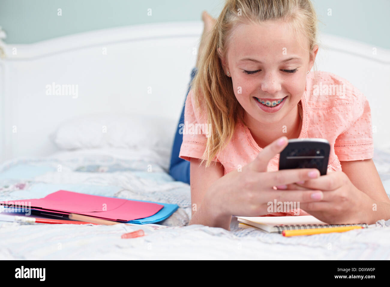Teenage girl lying on bed and using cellphone Stock Photo Alamy