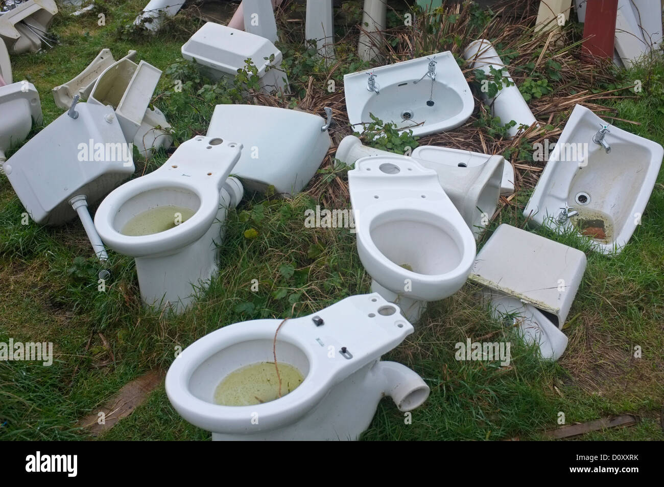 Old porcelain toilet bowls and sinks in a reclamation yard Stock Photo