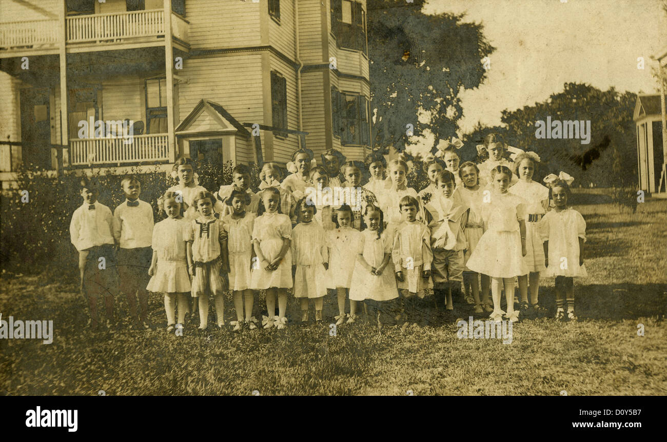 Circa 1890s cabinet card photograph, a group of children outside a large Victorian home, probably New England, USA. Stock Photo