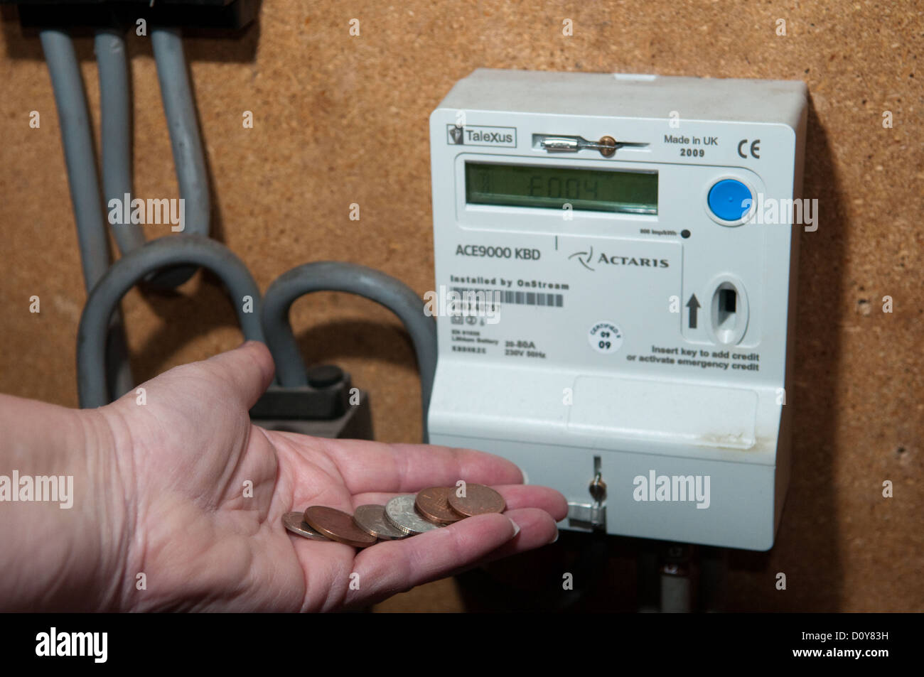 Pensioner in fuel poverty puts a handful of coins into a gas and electricity meter to keep warm in winter Stock Photo