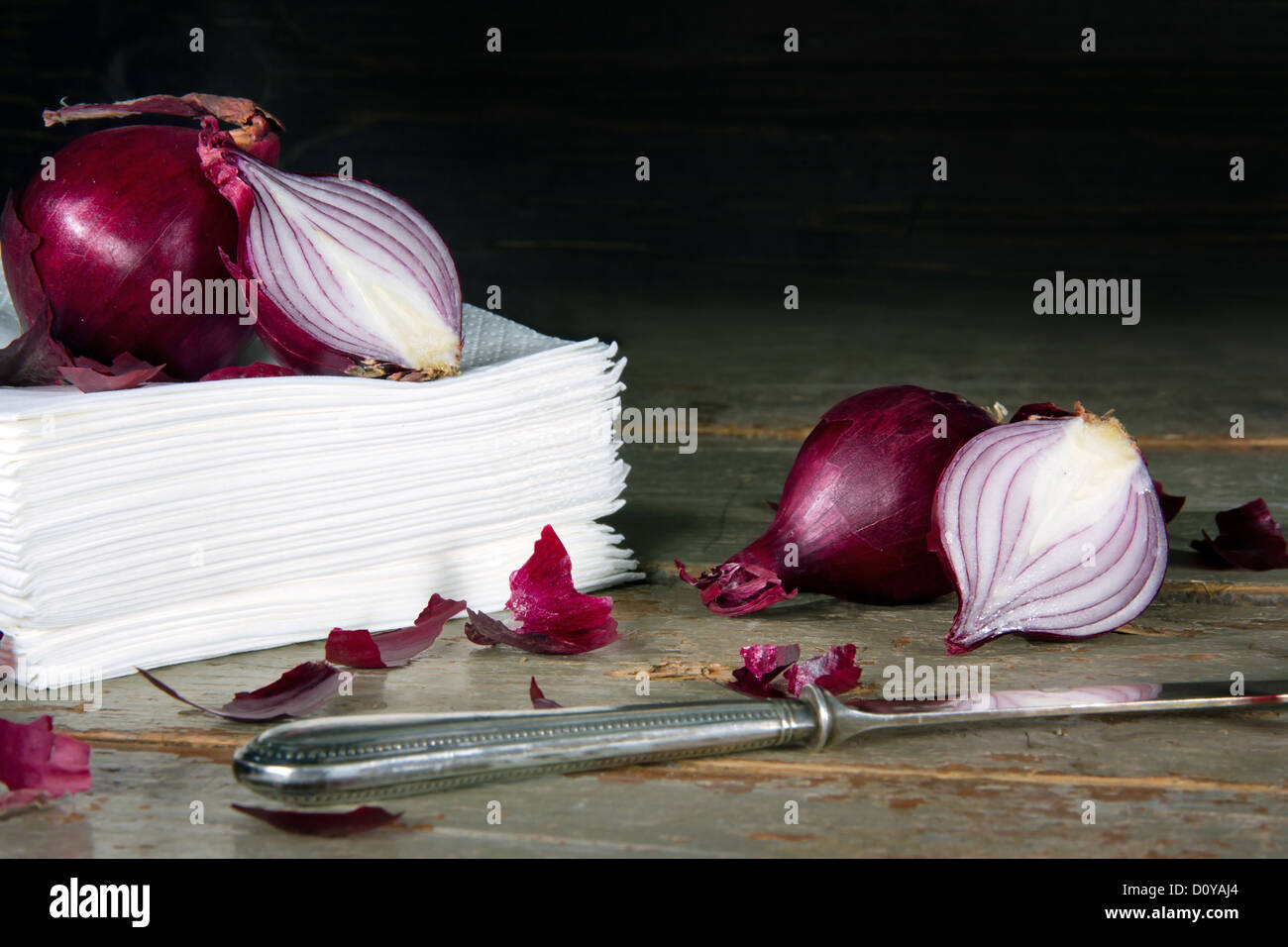 Red onions on a pile of paper tissues, rustic wooden dark background