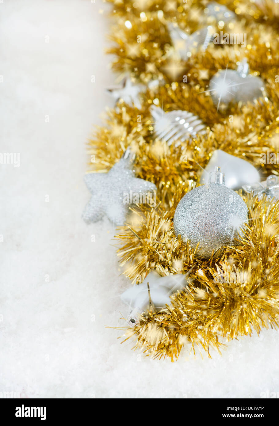 Silver Christmas decorations and golden tinsel on snow with sparkles, copy space Stock Photo