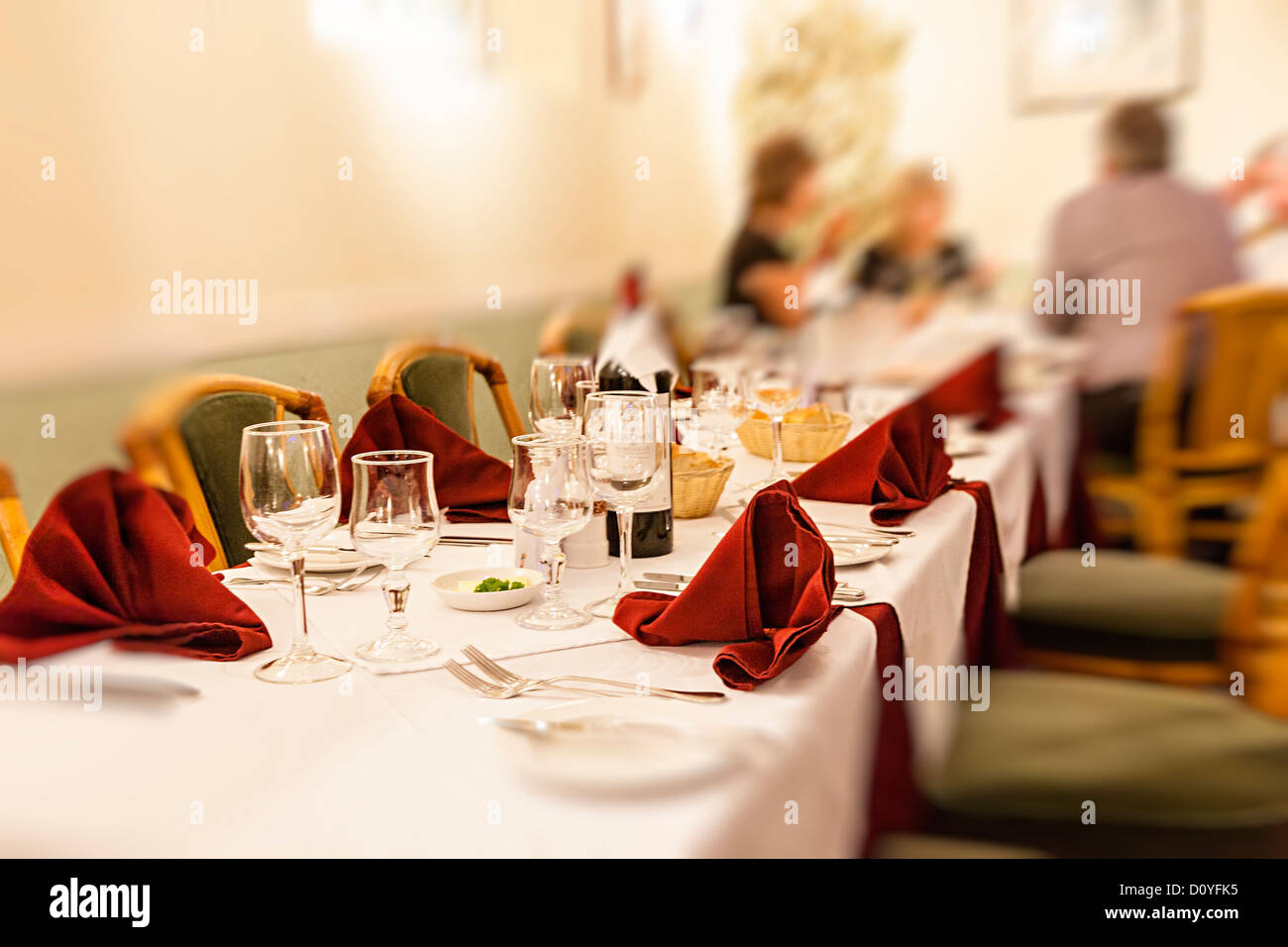 People in restaurant with focus on table with places laid ready, UK Stock Photo