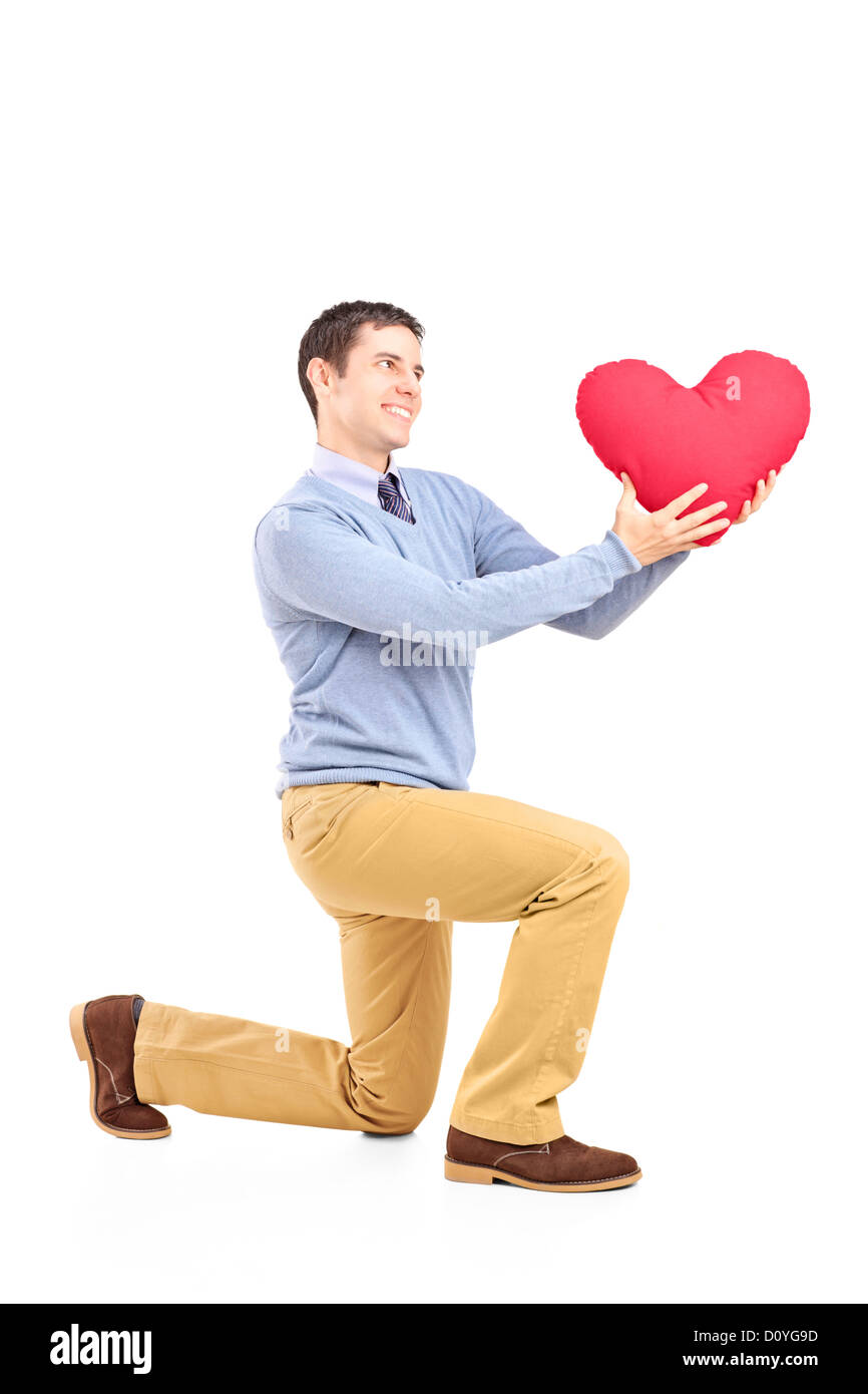 Smiling male kneeling with red heart shape object isolated on white background Stock Photo