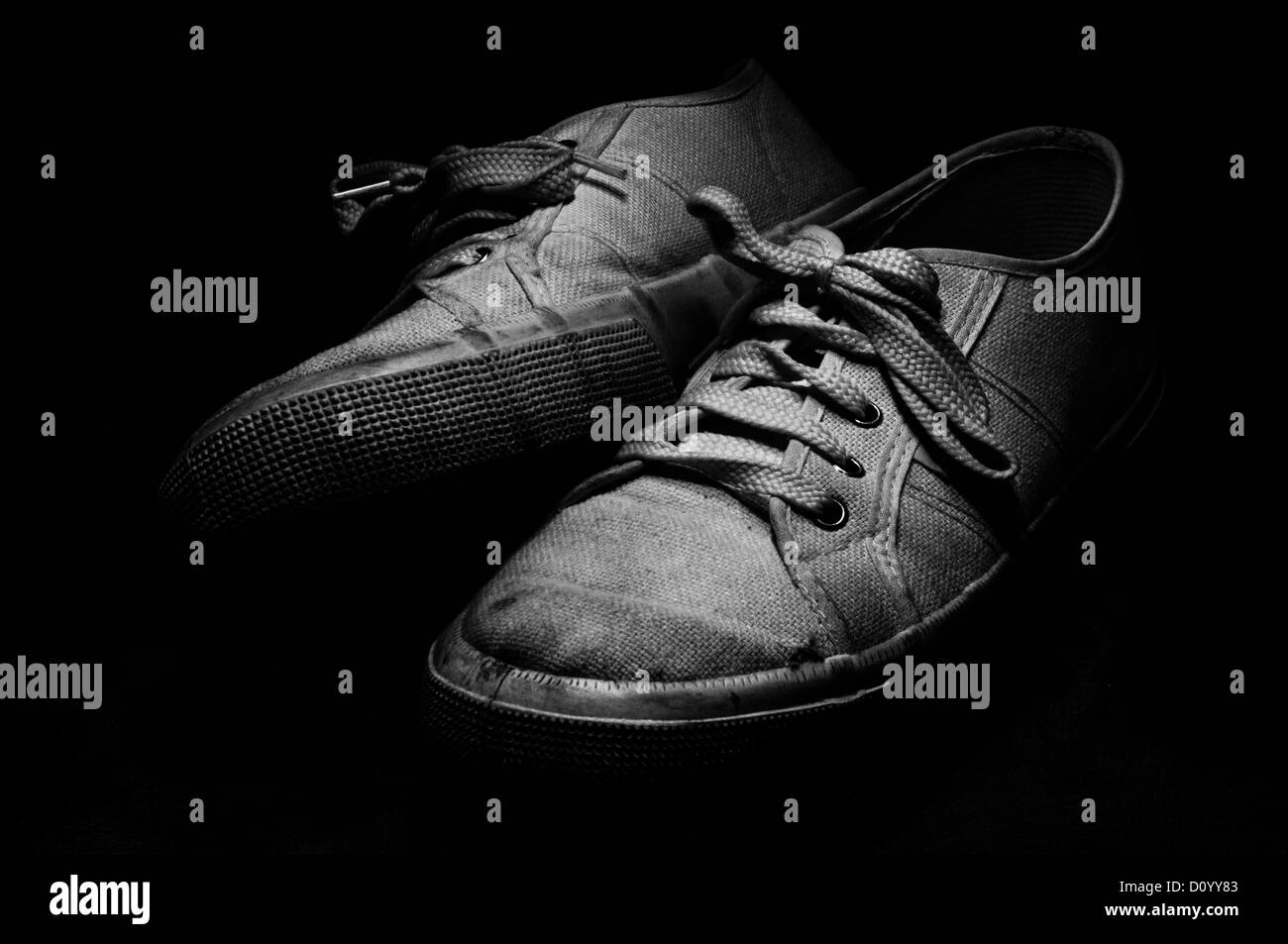 Old and used white tennis shoes on black background Stock Photo