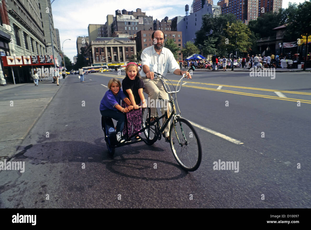 A father test rides a bicycle with two small children in a sidecar at an Alternative Cycling Festival in Union Square Park Stock Photo