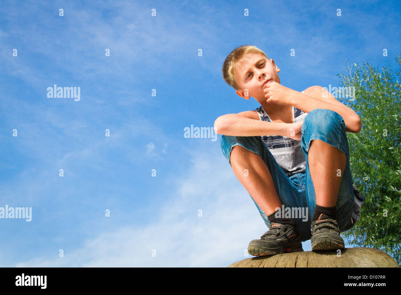 happy boy sitting on a stump in the park Stock Photo - Alamy