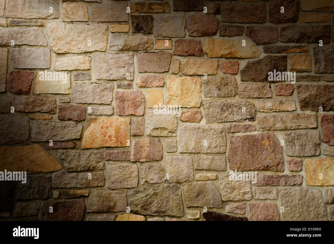 Masonry Wall of Multicolored Stone Blocks Lit Diagonally Stock Photo