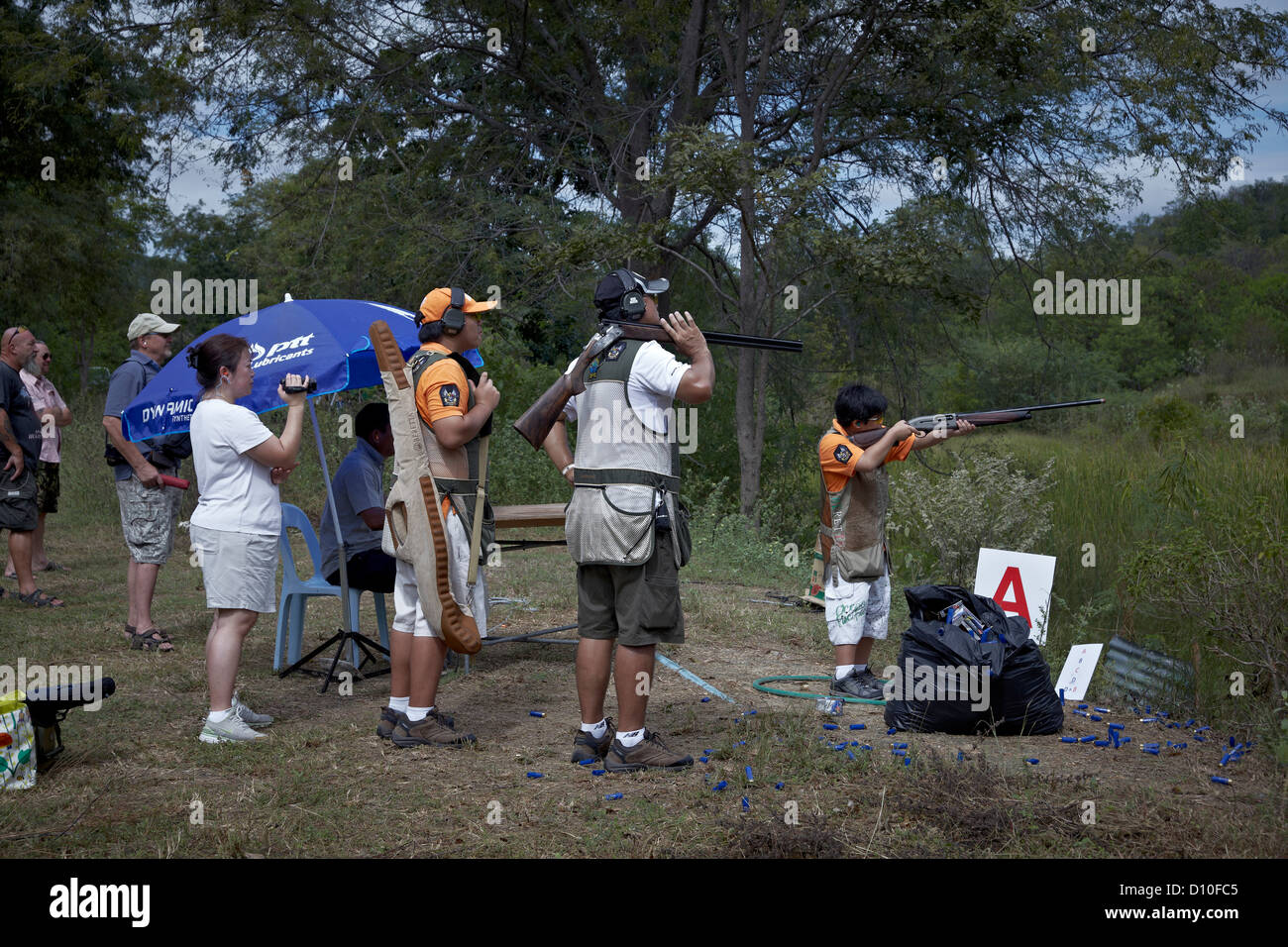 Clay pigeon shooters watching a young boy shooting Stock Photo