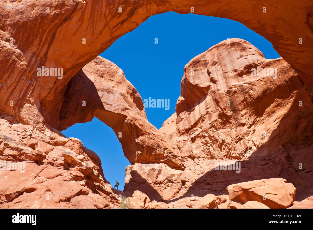 Hiker stood in the archway at Double Arch Arches national park, near Moab, Utah United States of America, USA Stock Photo