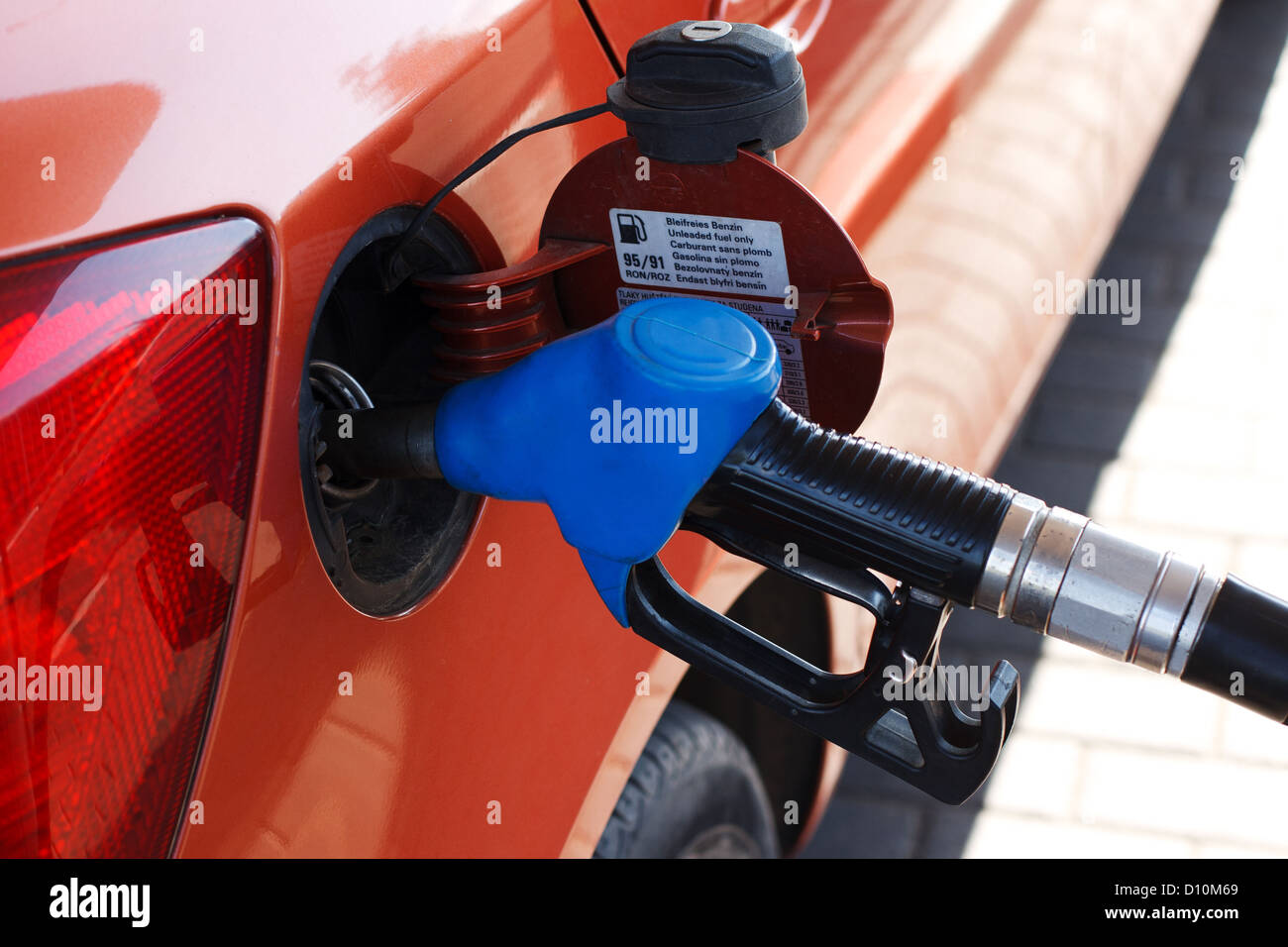 orange car at gas station being filled with fuel Stock Photo