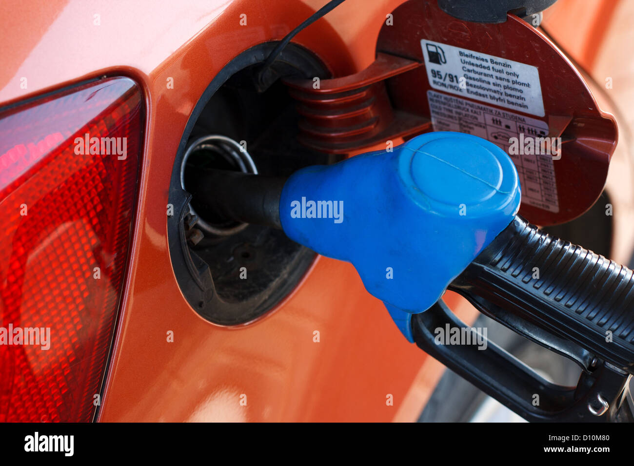 orange car at gas station being filled with fuel Stock Photo