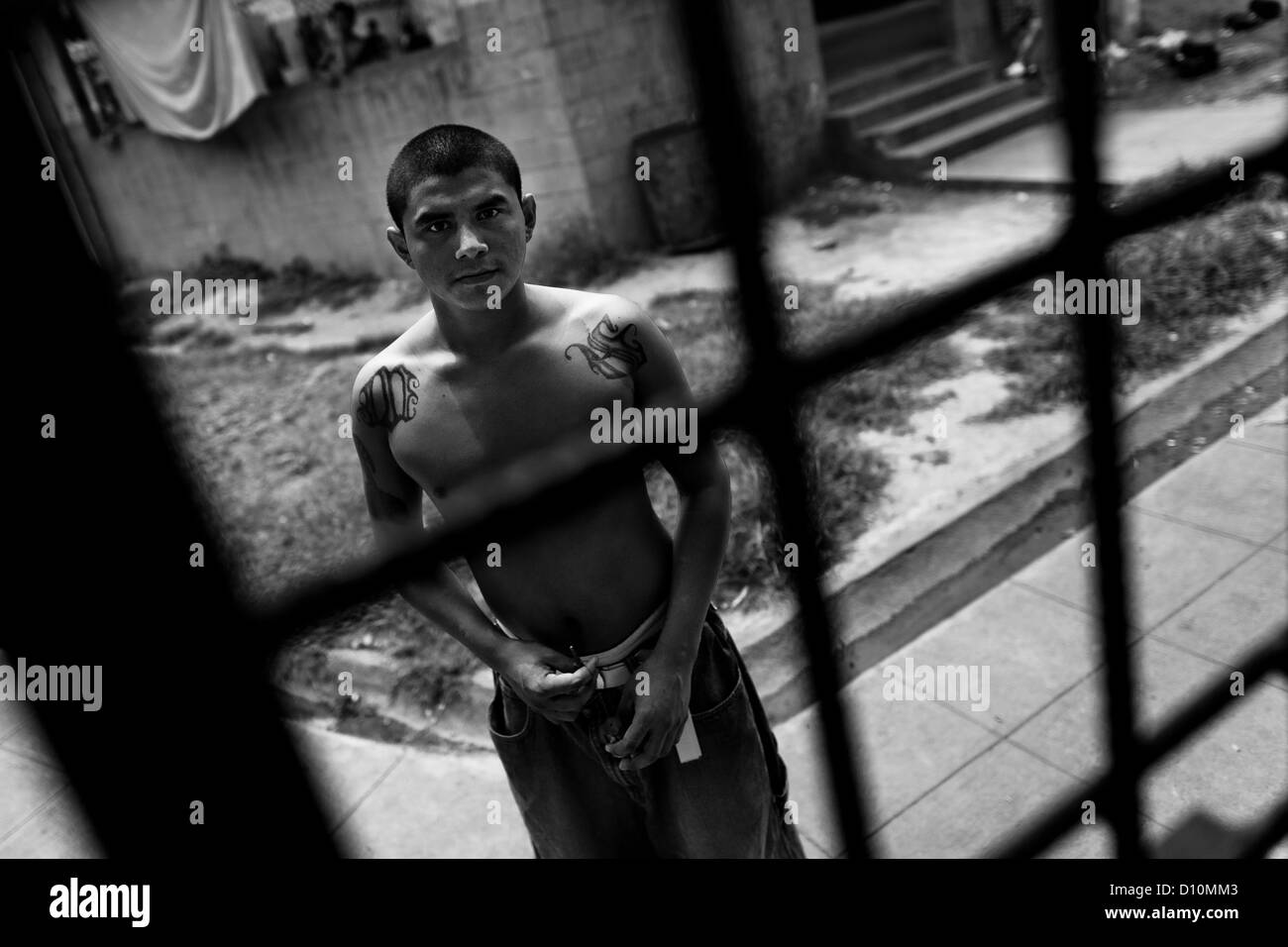 A member of the Mara Salvatrucha gang (MS-13) stands behind the bars in the prison of Tonacatepeque, El Salvador. Stock Photo