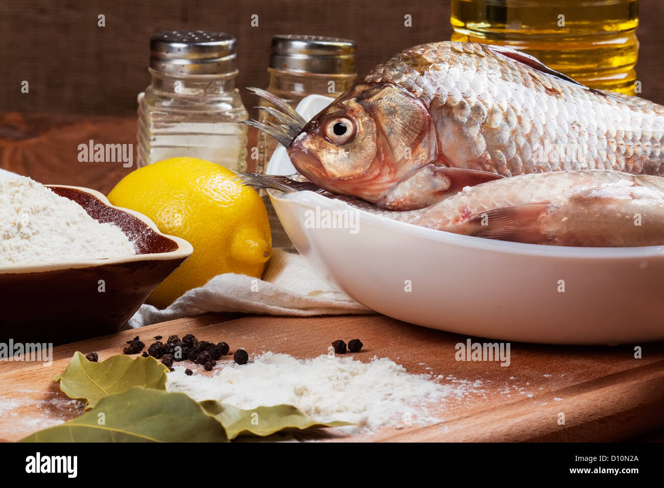 Fresh carp on a kitchen table with lemon and flour Stock Photo