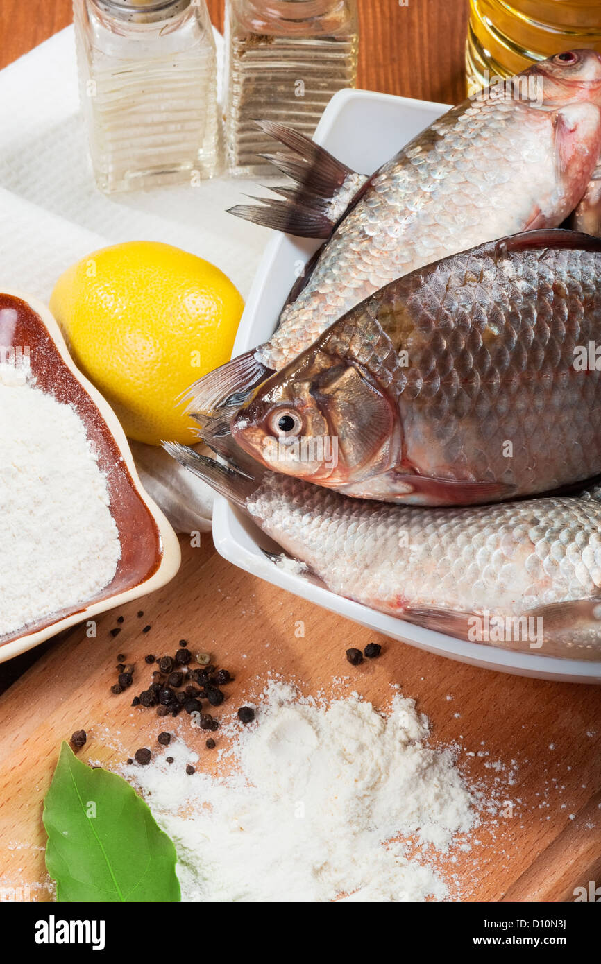 Fresh carp on a kitchen table with lemon and flour Stock Photo