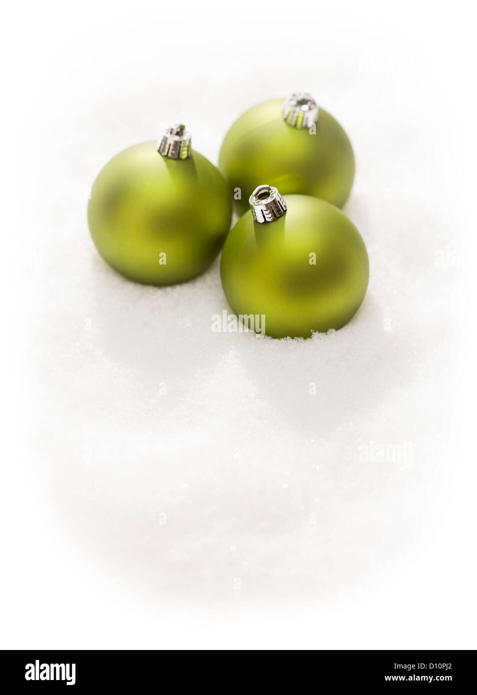 Three Green Christmas Ornaments on Snow Flakes Isolated on a White Background. Stock Photo
