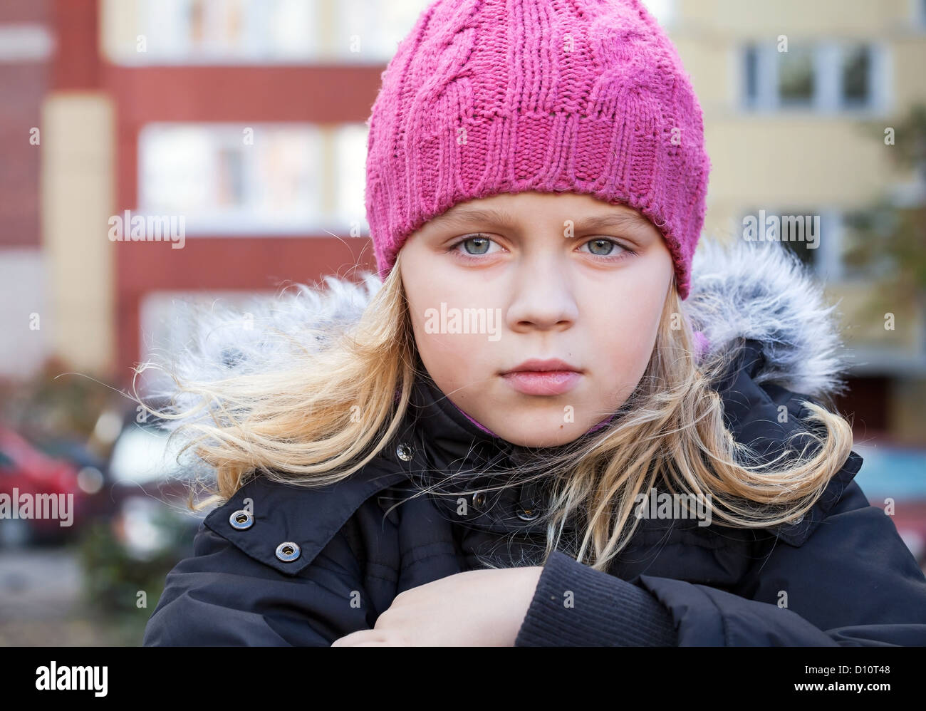 Little beauty blond girl looks thoughtfully into the distance. Outdoor street city portrait. Stock Photo