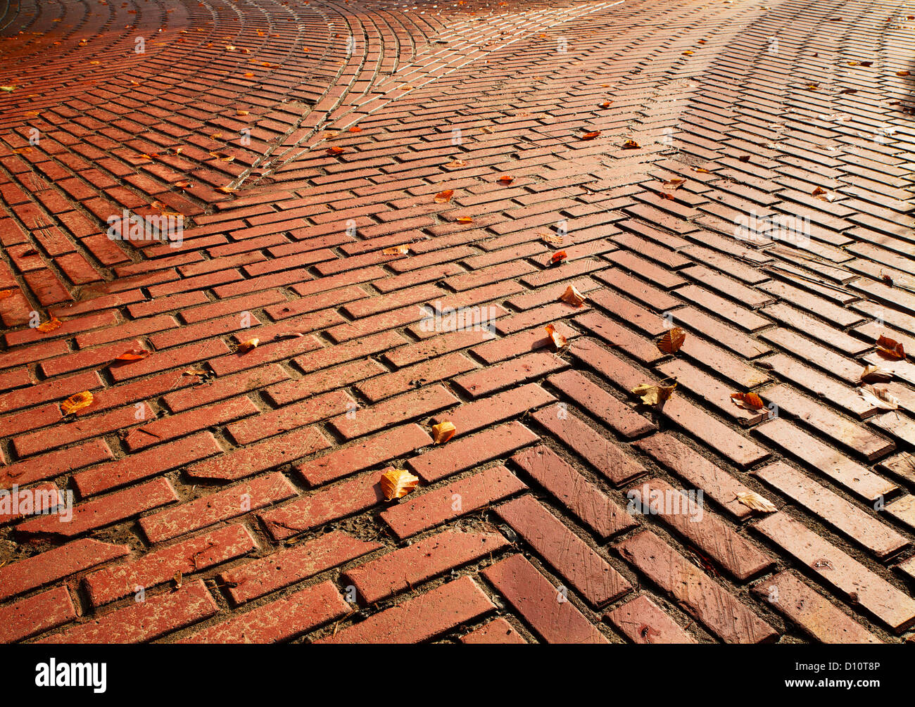 Red brick road split into two directions with herringbone pattern requiring a decision Stock Photo