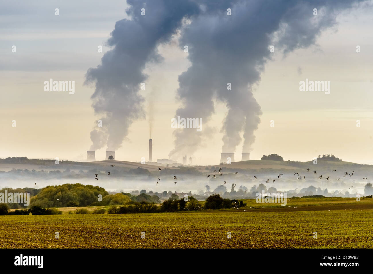 Distant view of Didcot Power Station with chimney emissions, contrasted against open fields and wildlife Stock Photo