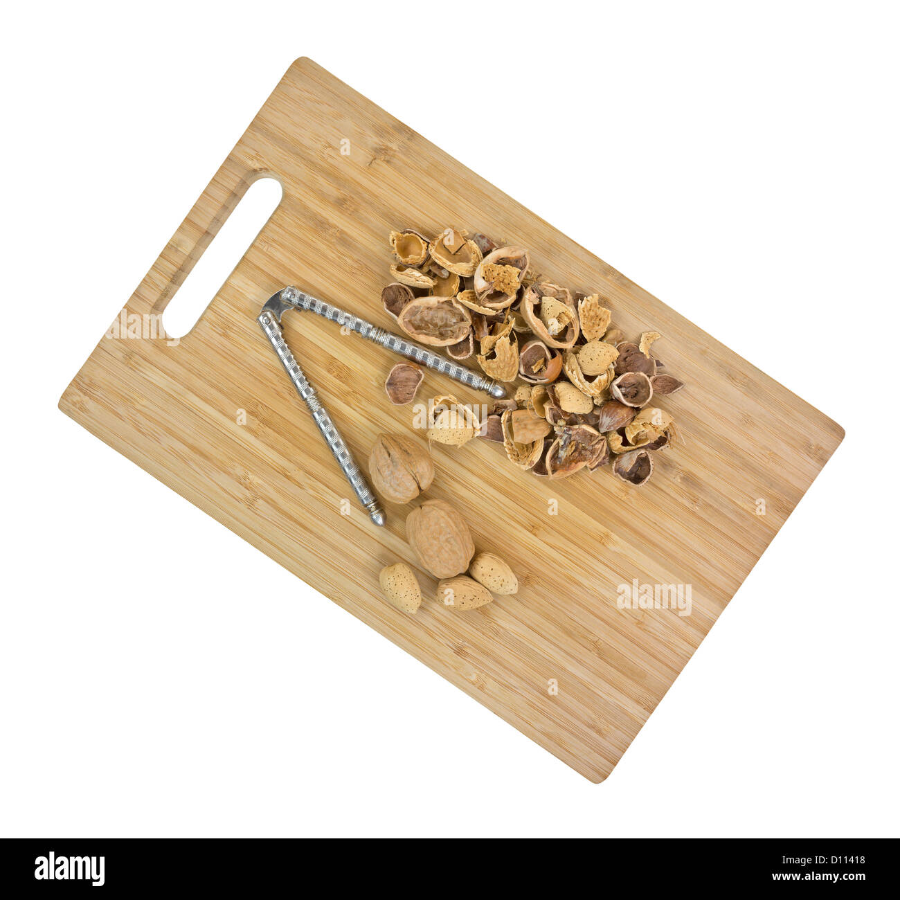 A group of shelled nuts with whole walnuts and almonds and nutcracker on a wood cutting board. Stock Photo