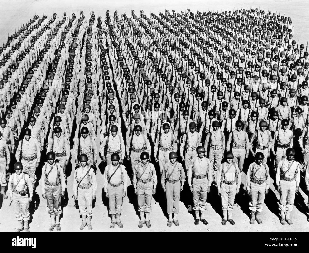 1940s WWII LARGE FORMATION U.S. ARMY INFANTRY SOLDIERS AT ATTENTION WEARING HELMETS UNDER ARMS RANK AND FILE Stock Photo