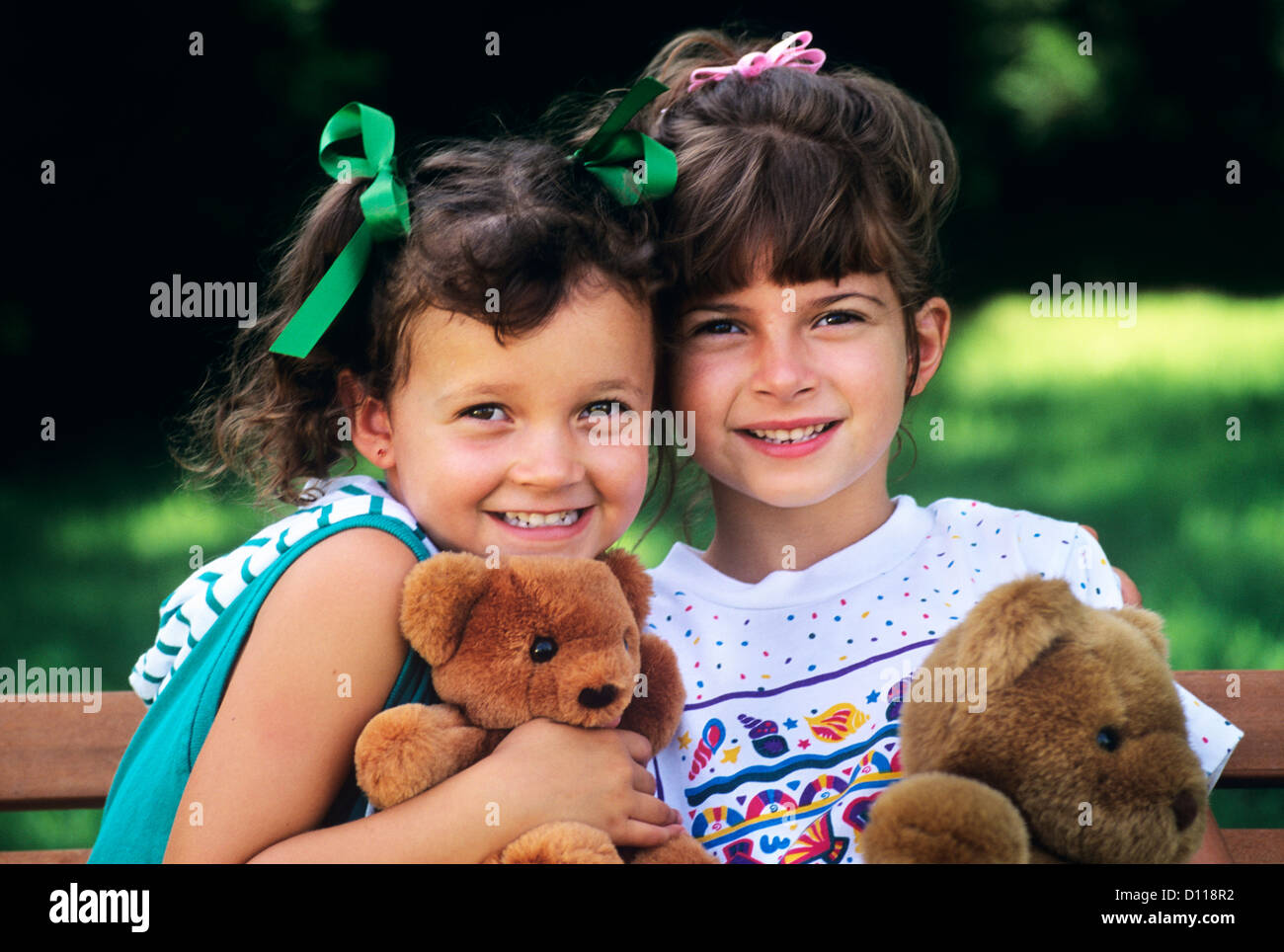 1990s TWO BRUNETTE GIRLS WITH TEDDY BEARS LOOKING AT CAMERA Stock Photo