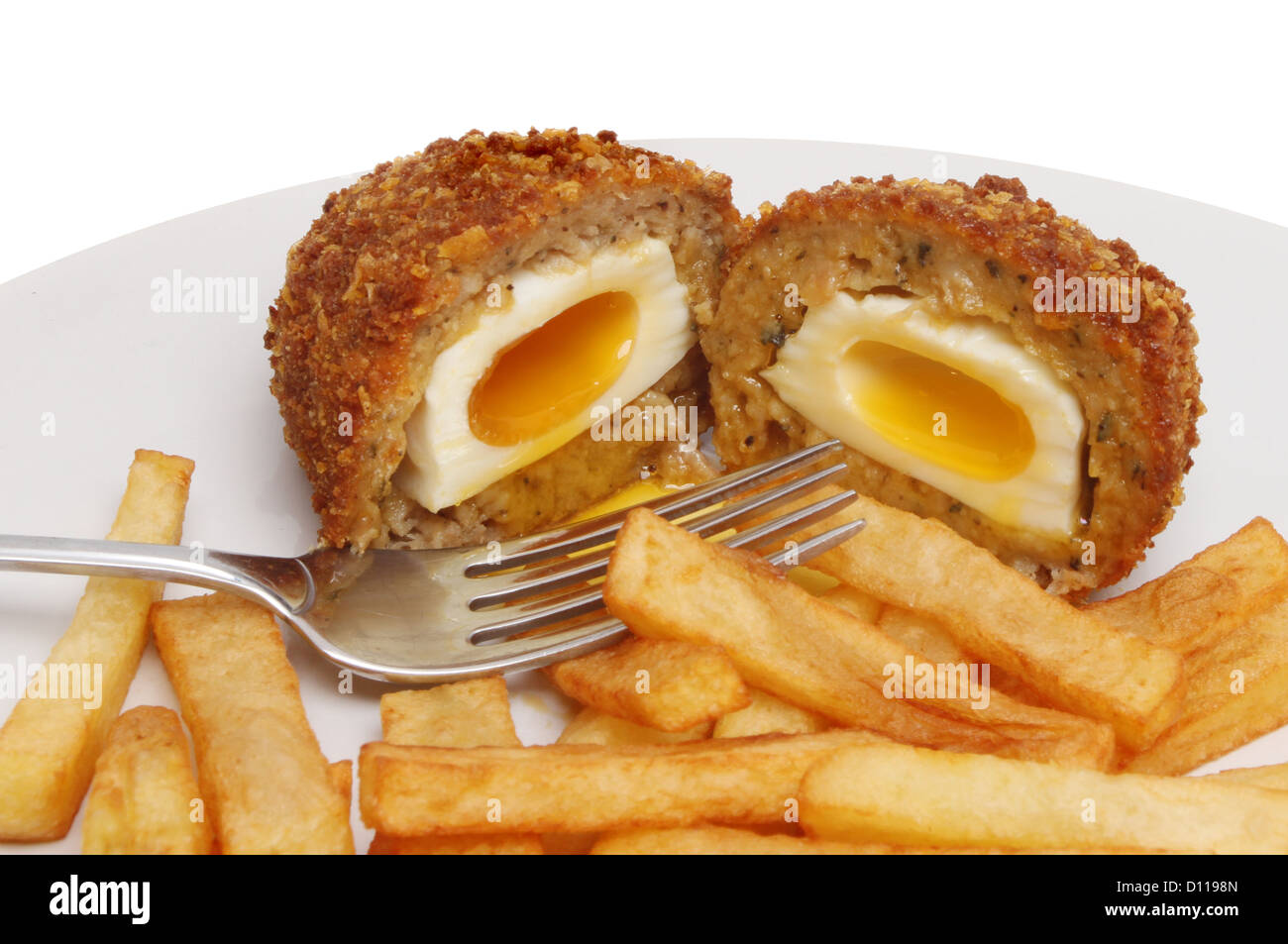 Runny Scotch egg and potato chips with a fork on a plate Stock Photo