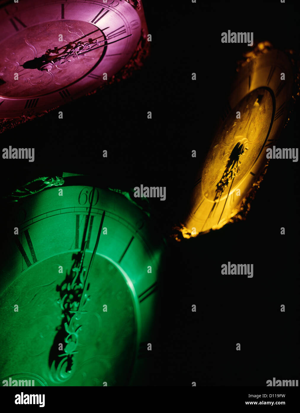 PINK YELLOW AND GREEN CLOCK FACES AT THE STROKE OF MIDNIGHT NEW YEARS