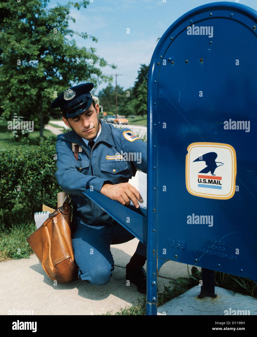 1970s MAILMAN TAKING MAIL OUT OF MAIL DROP BOX Stock Photo