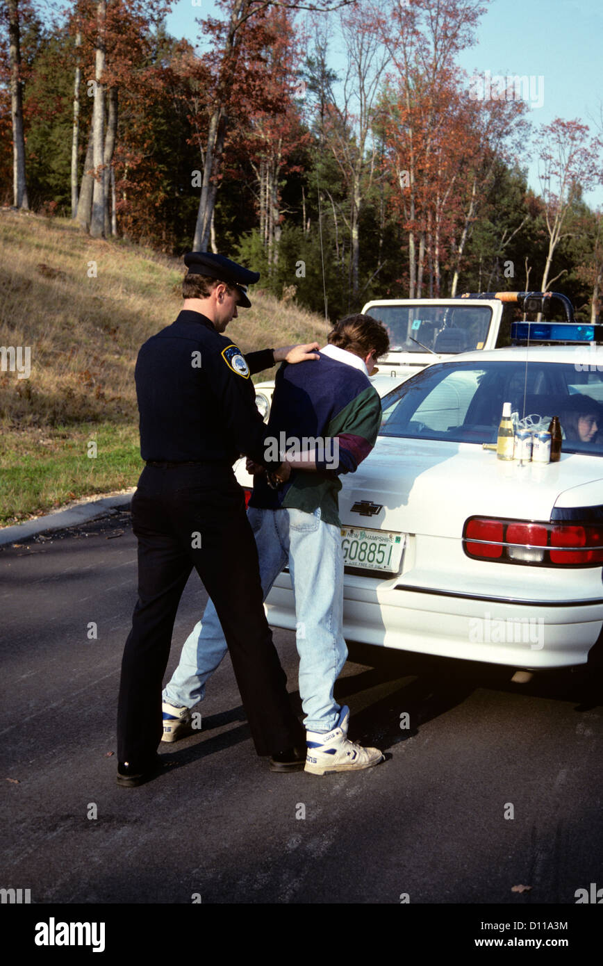 1990s POLICE OFFICER ARRESTING CUFFING MOTORIST FOR DRUNK DRIVING Stock Photo
