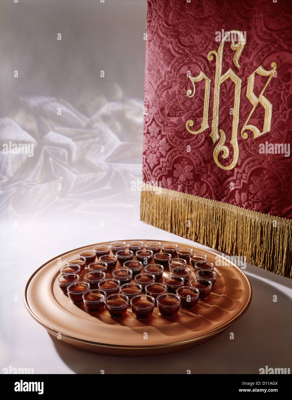 RELIGIOUS STILL LIFE OF TRAY OF WINE OFFERINGS FOR COMMUNION AND EMBROIDERED CLOTH WITH IHS Stock Photo