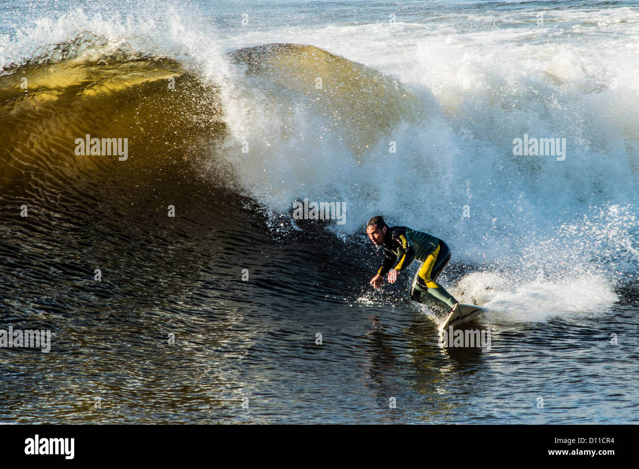 Aberystwyth Wales UK Surfers riding the waves at the mouth of the harbour in the warm autumn sunshine Stock Photo
