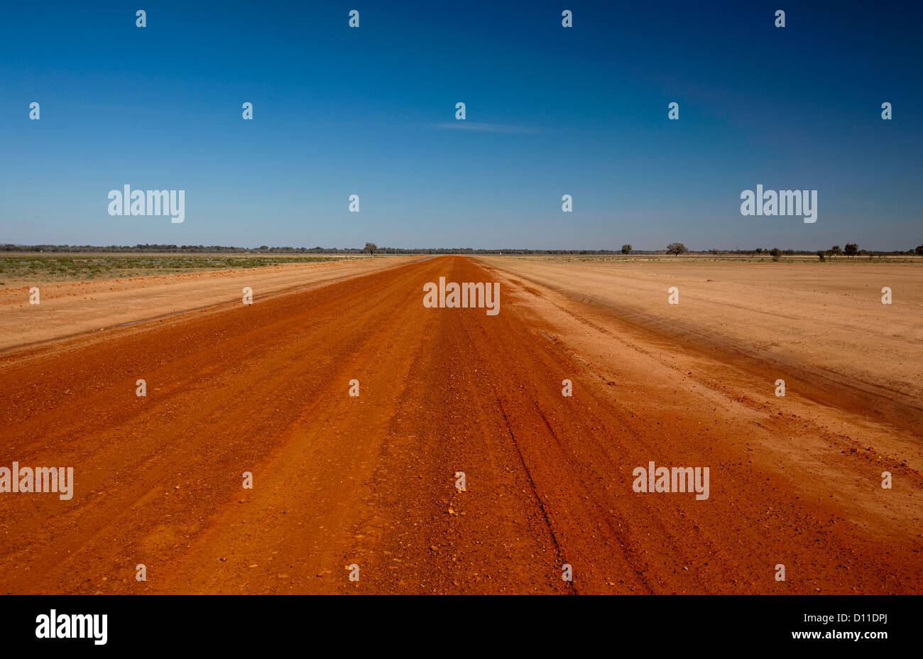 Long red Australian outback road across barren desert landscape and treeless plains of north-western NSW Australia to the far horizon Stock Photo