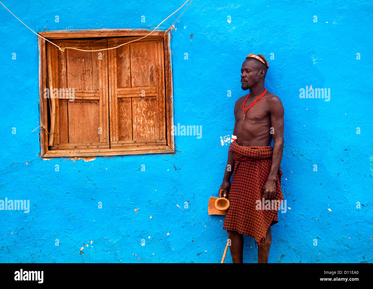 Portrait Of A Dassanech Tribe Man With Headrest Posing Outside A Blue Painted House, Omorate, Omo Valley, Ethiopia Stock Photo
