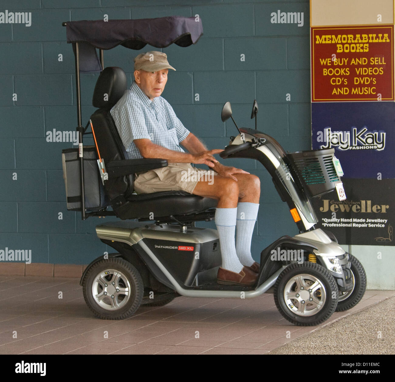 Elderly man - pensioner - on electric mobility scooter on city pavement in Australia Stock Photo